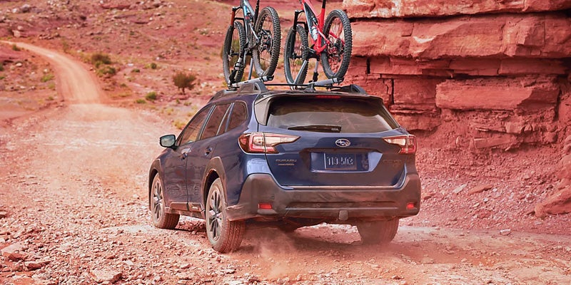 Rear side view of Subaru Outback driving on dirt road